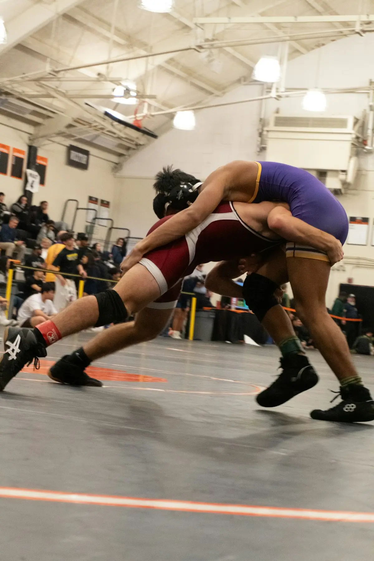 two wrestlers competing in a match with a crowd watching, scene for takedown and pin puns
