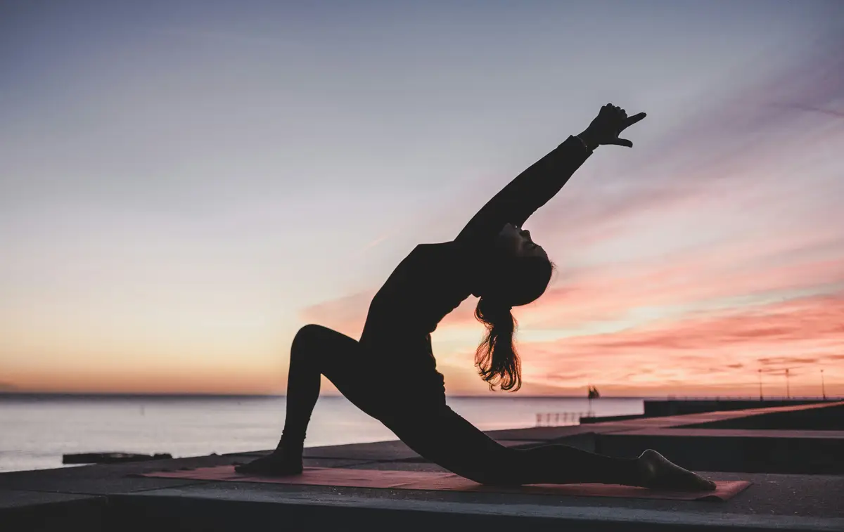 silhouette of a woman holding a yoga pose at sunset, scene for yoga puns and yoga pose puns